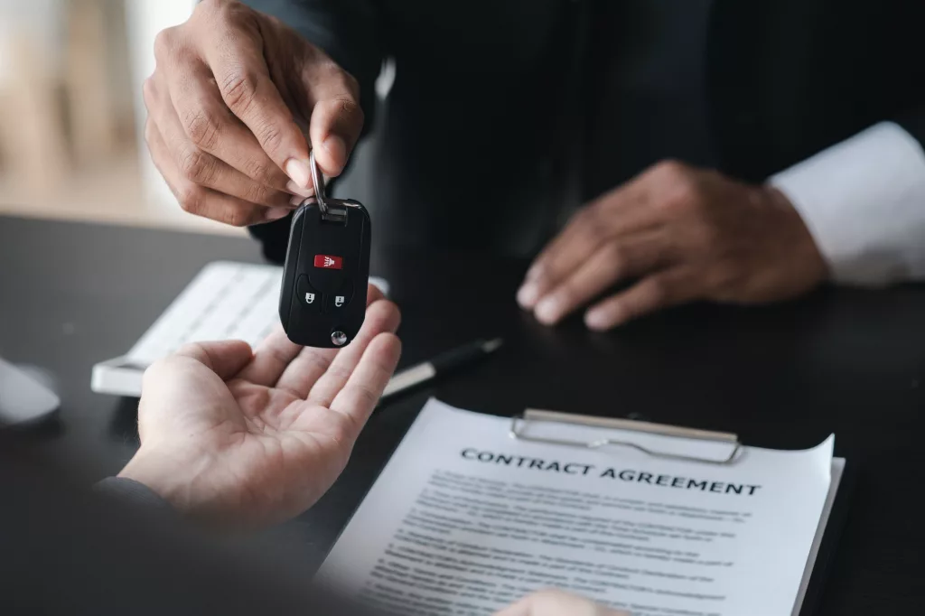 A car rental company employee pointed out the renter to sign the rental agreement after discussing t
